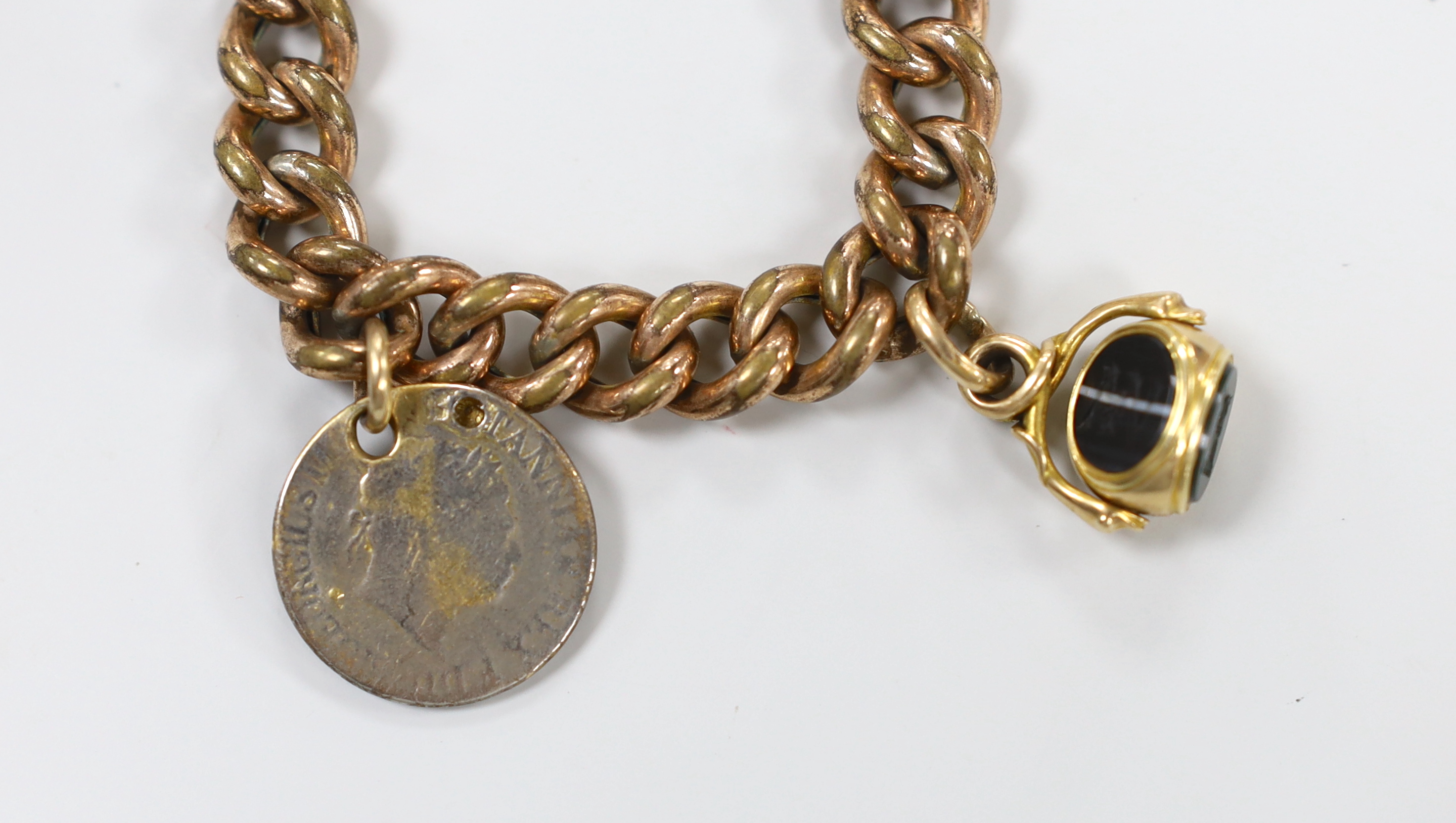 A Victorian gilt metal curb link bracelet, hung with a yellow metal and chalcedony set spinning fob and a worn coin.